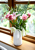 Jug of roses and lilies on windowsill of Gloucestershire cottage England UK
