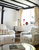Floral armchair at window in timber-framed living room Buckinghamshire cottage England UK