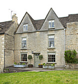 Stone terraced house exterior with pitched attic windows in Tetbury, Gloucestershire, England, UK