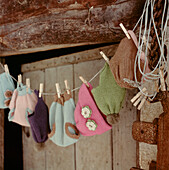 Reihe von Strickmützen an einer Wäscheleine im Gartenzimmer oder in der Veranda aufgehängt