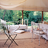 Canvas tent awning in country garden terrace with dining area and daybed
