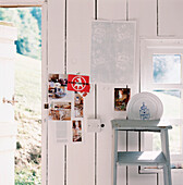 White washed panelled wood wall in a garden workshop with postcards on wall and painted vintage ladder