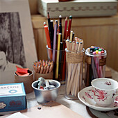 Artists desktop with pots of different coloured pens and pencils