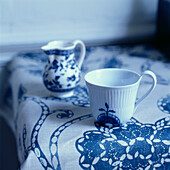 Tabletop detail with blue and white patterned tablecloth and crockery home wares