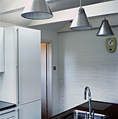 Minimal beamed black and white kitchen with stainless steal hanging lights and kitchen sink and painted brickwork