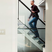 Man walking up a metal staircase in an open plan contemporary apartment