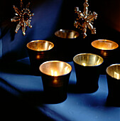 Golden glowing tea light candles in black holders twinkling on a shelf