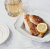 Dish of cooked chicken with lemon on a white tabletop
