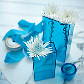 Detail of turquoise blue glass vases with white Chrysanthemum flower display