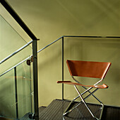 Treppenhaus aus Metall und Glas mit grün gestrichenen Wänden und einem Klappstuhl auf dem Treppenabsatz