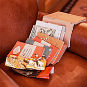 Scattered books and chocolate wrappers on a brown leather armchair