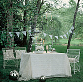 Romantic table setting for entertaining in a green tree lined garden