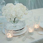 Romantisch gedeckter weißer Sommertisch für Gäste in einem Garten