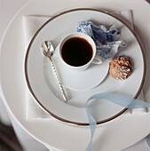 White formal place setting with coffee cup and biscuit