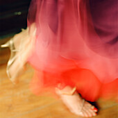 Atmospheric detail of a woman's feet in a red dress dancing 