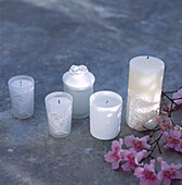 Display of white ornate candles and flowers on a garden tabletop