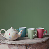 Teapot and mugs on a tabletop in pastel shades