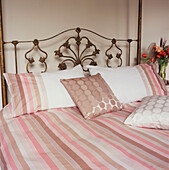 Ornate double bed with pink striped bed linen