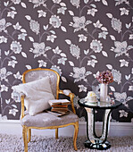 Bold patterned wallpaper in a living room with upholstered chair and mirrored side table