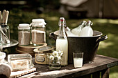 Butter dish and storage tin with plates and a bucket of lemonade on table in garden, UK