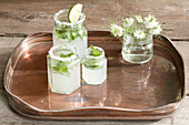 Lemonade in jam jars on brass tray with cut flowers, UK