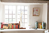 Books and ornaments on window shelf, UK