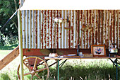 Außenküche mit Tapeziertisch unter einem Vordach neben einer rustikalen Schäferhütte auf einem Feld
