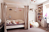 Großer weicher Eisbär auf einem Einzelbett mit Vorhängen in einem Mädchenzimmer in einem modernen Haus in London, England, UK