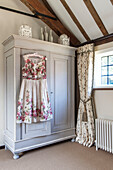 Summer dress hangs on wardrobe at bedroom window in Surrey barn conversion England UK