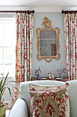 Sitting room detail with gilt framed mirror and patterned curtains and cushions in Wiltshire country house England UK