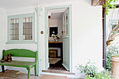 Boots on green bench seat at open front door of Surrey cottage England UK