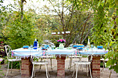 Tisch auf gemauerten Stützen mit schmiedeeisernen Stühlen auf der Gartenterrasse eines Landhauses in Surrey England UK