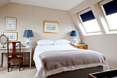 Attic bedroom with matching blue china bedside lamps in contemporary Chelsea home London UK