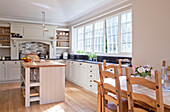 Open plan sunlit kitchen with wooden table and chairs in Surrey home England UK
