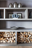Metallic homeware and firewood on shelving unit in in Lakes home, England, UK