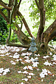 Fairy statue collecting fallen blossom in Haslemere garden, Surrey, UK