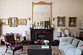 Gilt mirror above fireplace framed with William Hoare pastels with William IV armchair in historic Somerset country house UK