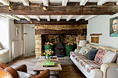 Stone fireplace with low beamed ceiling in Cirencester farmhouse Gloucestershire UK