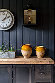 Clock and lantern with ceramic urns on sideboard in Cirencester barn conversion Gloucestershire UK