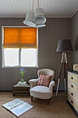 Stuhl am Fenster mit umgedrehter Kiste und dreibeiniger Stehlampe in Cirencester home Gloucestershire UK