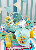 Turquoise painted hat and baskets on suitcase with bottles of orange juice