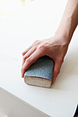 Woman works with sanding block in UK home