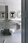 Grau gefliestes Badezimmer mit modernen Kunstwerken und weißen Armaturen in einem Haus in Farnham, Surrey, Großbritannien