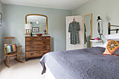 Gilt framed mirror above wooden chest of drawers with rocking chair in bedroom of Reading home Berkshire England UK