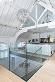Open plan kitchen with polished concrete surfaces and glass banister in converted London courthouse UK