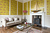 Yellow wallpaper patterned with pink flowers and two seater sofa in Georgian Grade II listed Surrey home UK