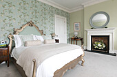 Gilt headboard on double bed with light green floral wallpaper in Georgian Grade II listed Surrey home UK