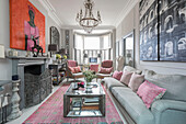 PInk hues and artwork with silver fireguard and table in living room of Victorian terrace Wandsworth London Uk