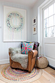 Vintage-Sessel und modernes Kunstwerk mit kreisförmiger Matte in einem Landhaus in Guildford, Surrey, Großbritannien