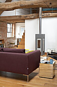 Lila Sofa im Wohnzimmer mit Balken in einer umgebauten walisischen Scheune
